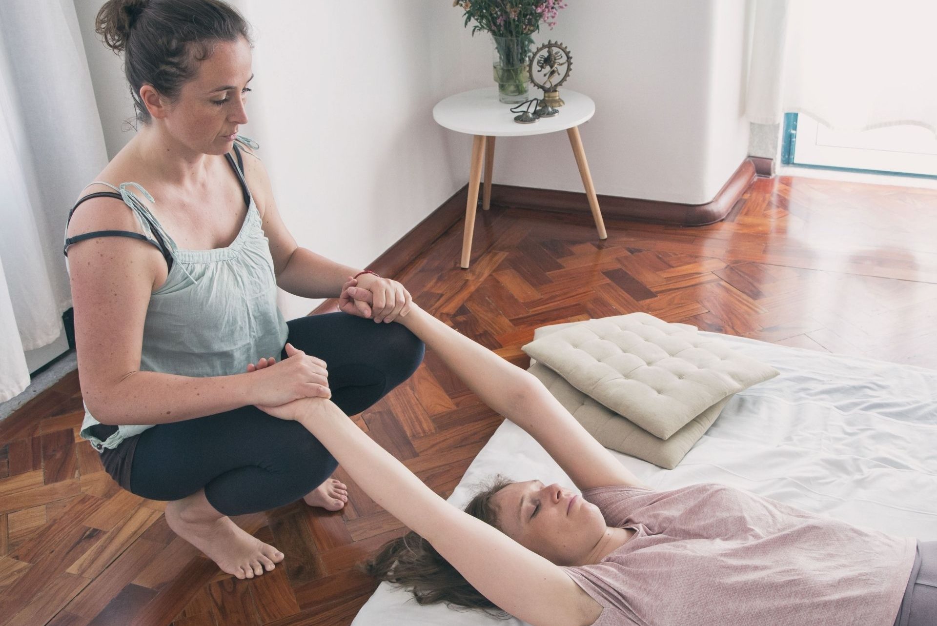 Katrin pulling the receiver's arms over their head for a stretch in a Thai Massage sequence